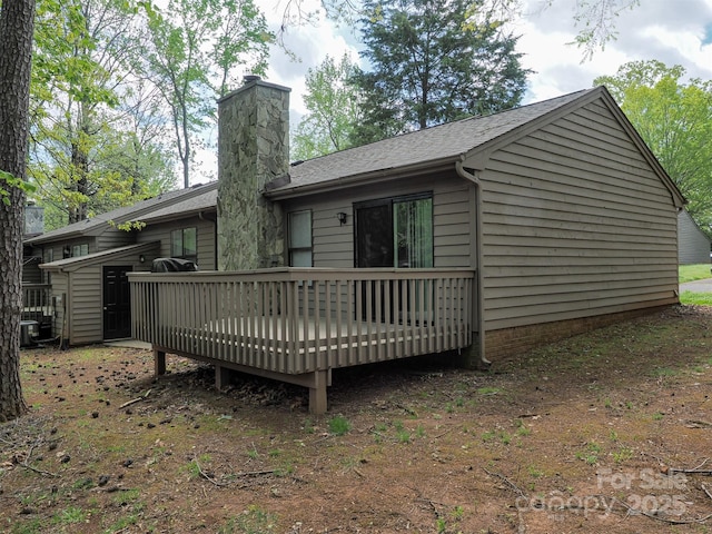 rear view of property featuring central AC unit, a wooden deck, a shingled roof, and a chimney