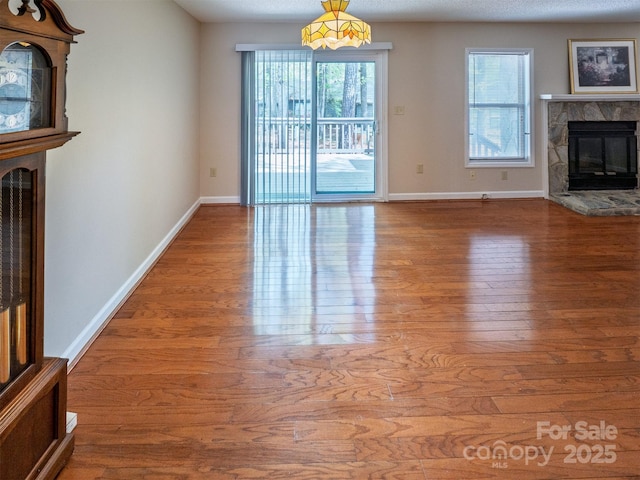 unfurnished living room with baseboards, wood finished floors, and a fireplace