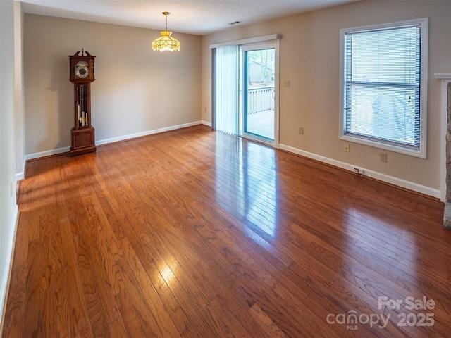 spare room with a brick fireplace, wood finished floors, and baseboards