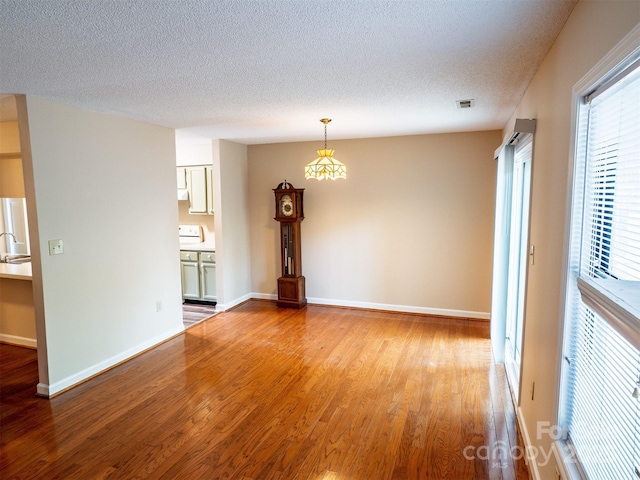 unfurnished room with a textured ceiling, light wood-style floors, and baseboards