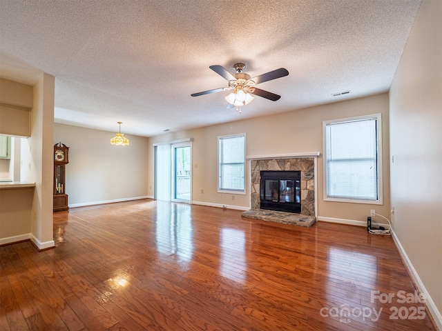 unfurnished living room with visible vents, a stone fireplace, a textured ceiling, and wood-type flooring