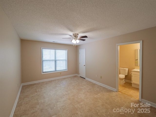 unfurnished bedroom featuring baseboards, light floors, a textured ceiling, and ensuite bathroom