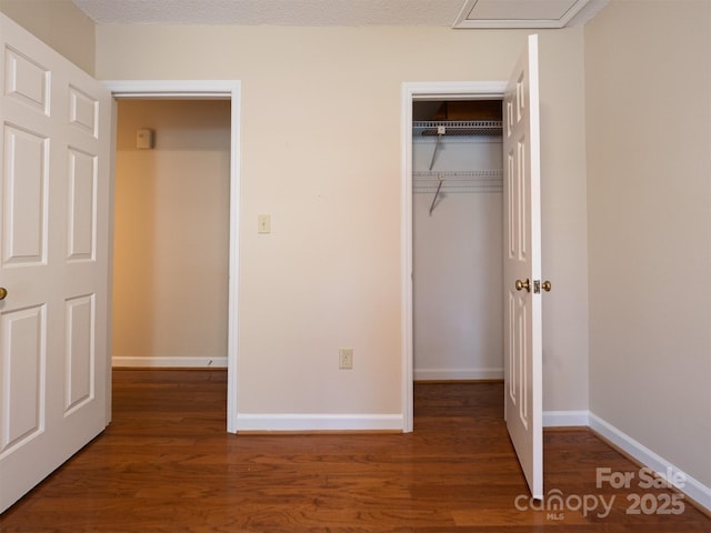 unfurnished bedroom featuring baseboards, wood finished floors, and a closet