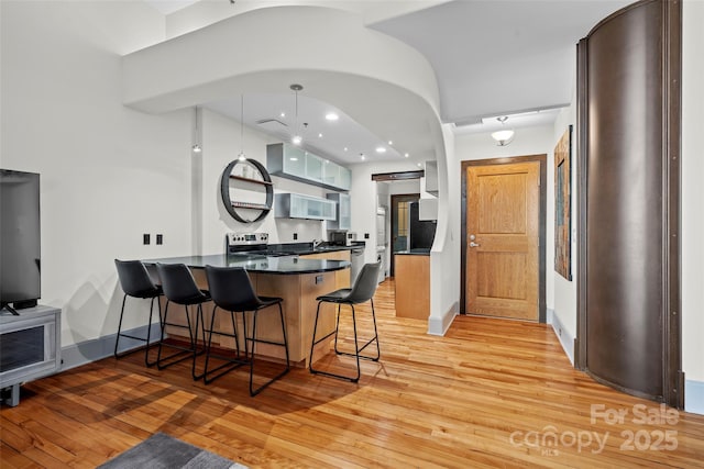 84 Walnut St Unit 203, Asheville, NC 28801 - kitchen featuring stainless steel appliances, a peninsula, a kitchen breakfast bar, light wood-style flooring, and dark countertops