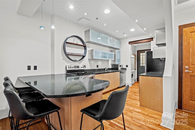 84 Walnut St Unit 203, Asheville, NC 28801 - kitchen featuring a breakfast bar area, light wood finished floors, a peninsula, appliances with stainless steel finishes, and recessed lighting