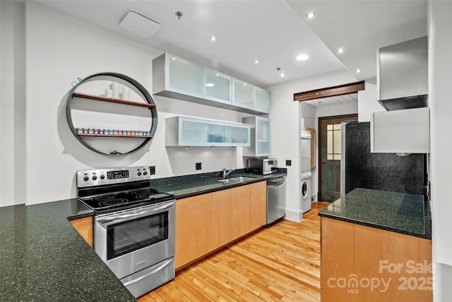 84 Walnut St Unit 203, Asheville, NC 28801 - kitchen featuring a sink, glass insert cabinets, light wood-style flooring, appliances with stainless steel finishes, and washer / clothes dryer