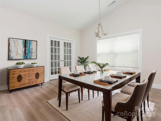 dining area featuring visible vents, an inviting chandelier, lofted ceiling, light wood-type flooring, and french doors