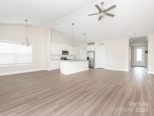 unfurnished living room with visible vents, a sink, baseboards, and ceiling fan