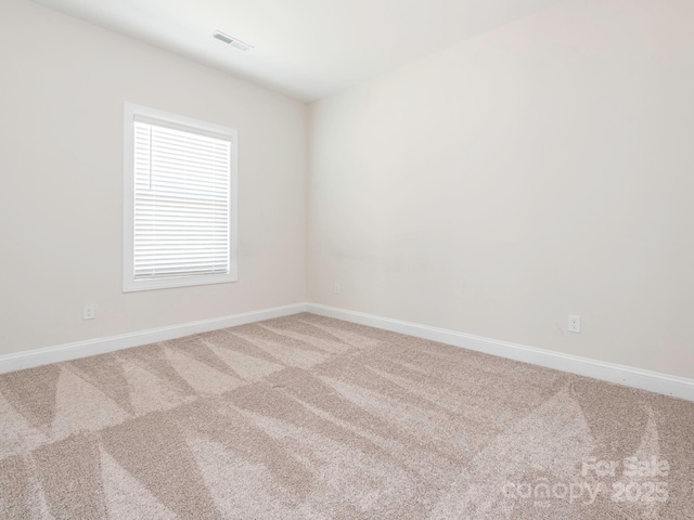 carpeted spare room featuring baseboards and visible vents