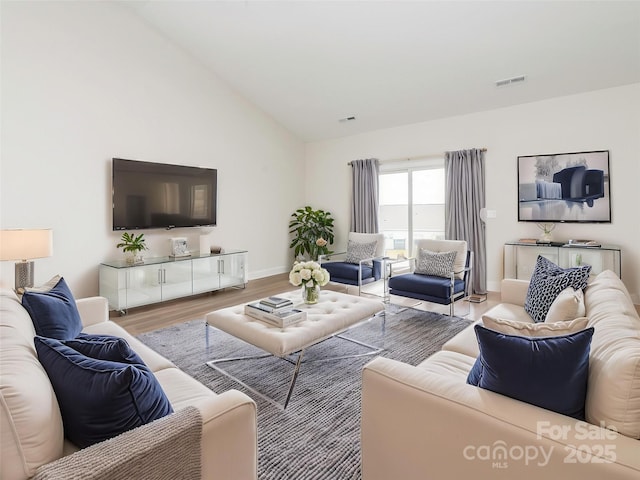 living room featuring baseboards, high vaulted ceiling, wood finished floors, and visible vents