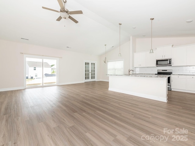 unfurnished living room with high vaulted ceiling, a sink, ceiling fan, and light wood-style floors