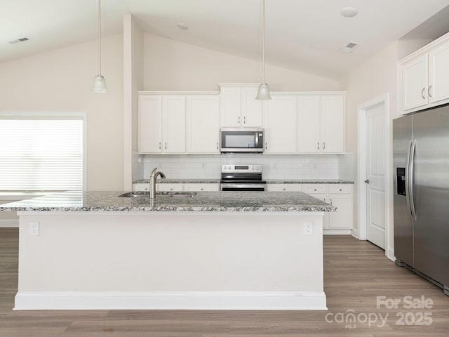 kitchen featuring light wood-style flooring, appliances with stainless steel finishes, a sink, and vaulted ceiling