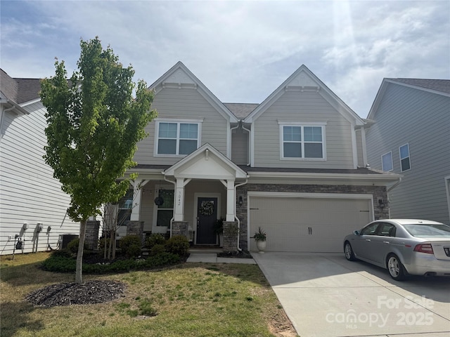 craftsman inspired home with a front lawn, stone siding, covered porch, concrete driveway, and a garage