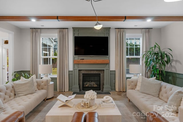 living room featuring beamed ceiling, recessed lighting, wood finished floors, and a fireplace with flush hearth