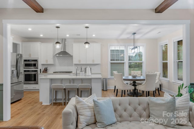living room with beamed ceiling, light wood-style flooring, and recessed lighting