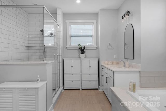 bathroom with a shower stall, a bath, and vanity