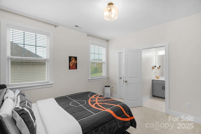 bedroom with ensuite bath, visible vents, baseboards, and light colored carpet