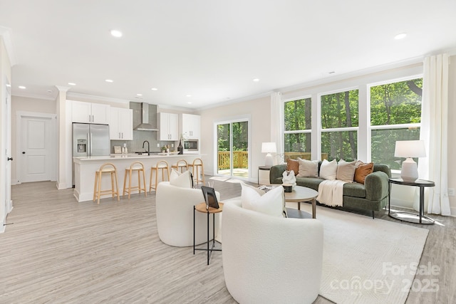 living area with crown molding, recessed lighting, and light wood-style flooring