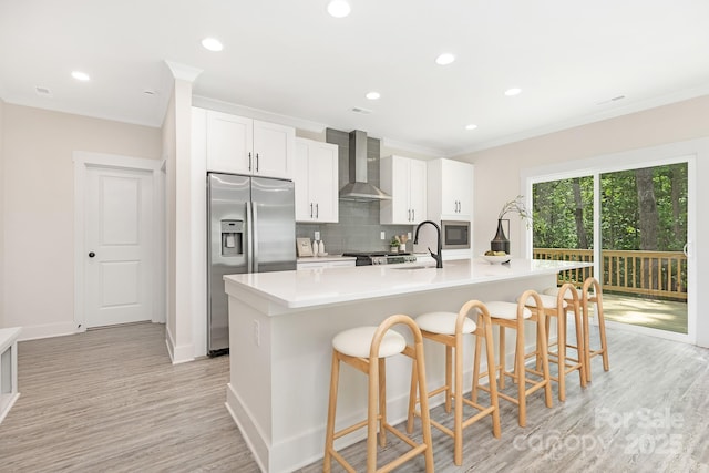 kitchen with wall chimney range hood, a sink, stainless steel appliances, a large island, and tasteful backsplash
