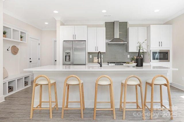 kitchen featuring built in microwave, a sink, stainless steel fridge, ornamental molding, and wall chimney exhaust hood