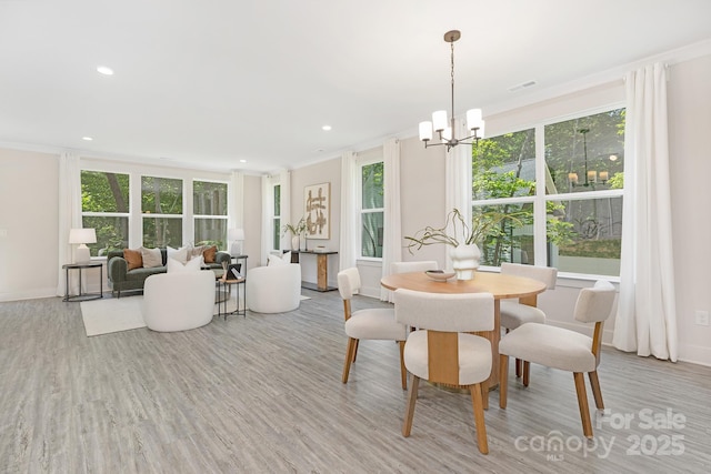 dining room with visible vents, crown molding, baseboards, light wood finished floors, and an inviting chandelier