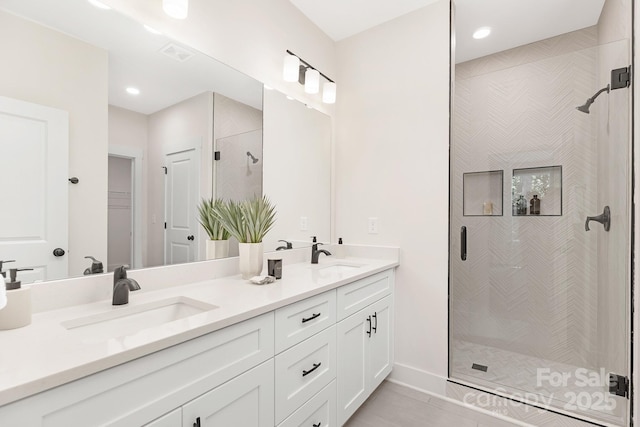 full bathroom with double vanity, a sink, visible vents, and a shower stall