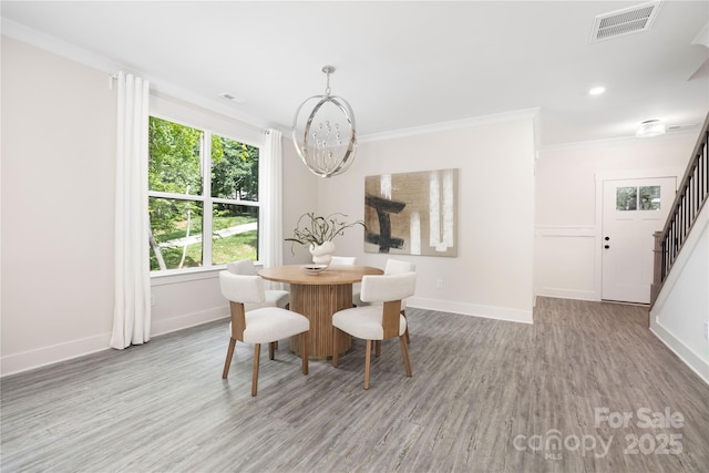 8937 Penstemons Dr, Charlotte, NC 28215 - dining space with stairs, a chandelier, wood finished floors, crown molding, and recessed lighting
