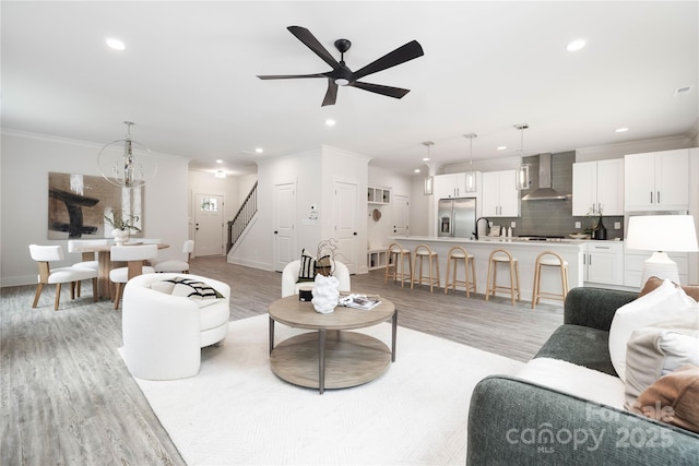 8937 Penstemons Dr, Charlotte, NC 28215 - living room with light wood finished floors, stairs, recessed lighting, ornamental molding, and ceiling fan