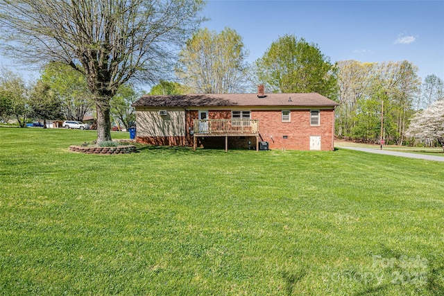 rear view of property with central AC unit, a deck, a yard, a chimney, and brick siding