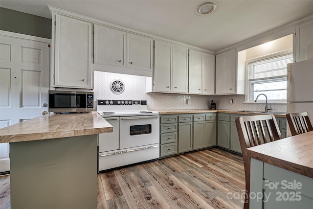 kitchen with white appliances, a sink, a peninsula, and light wood finished floors
