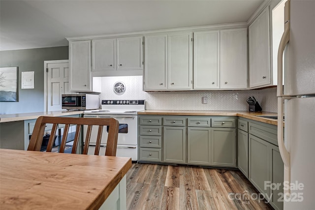 kitchen with white appliances, butcher block counters, light wood finished floors, backsplash, and green cabinetry