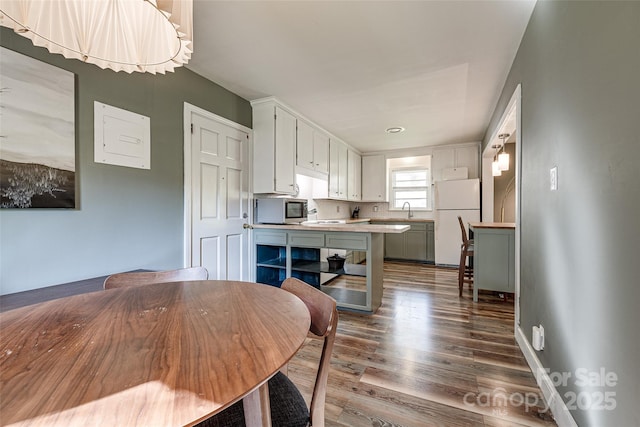 kitchen with stainless steel microwave, light countertops, freestanding refrigerator, dark wood finished floors, and a sink