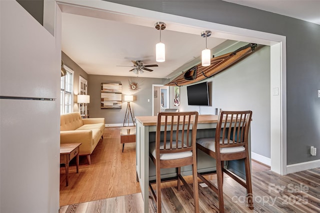 dining space featuring light wood-type flooring, ceiling fan, and baseboards