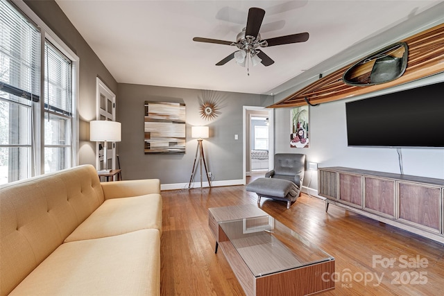 living room with baseboards, a ceiling fan, and wood finished floors