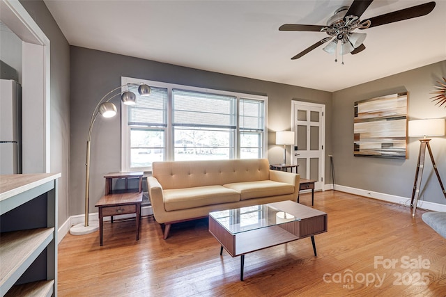 living room featuring light wood finished floors, baseboards, and a ceiling fan