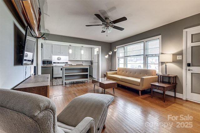 living area with light wood-style floors and a ceiling fan