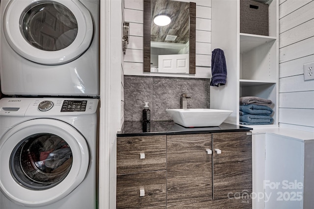 laundry area featuring laundry area, a sink, and stacked washer and clothes dryer