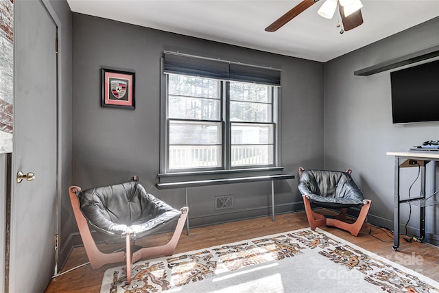 living area featuring baseboards, wood finished floors, and ceiling fan