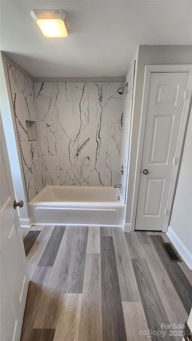 full bathroom featuring shower / tub combination, baseboards, visible vents, and wood finished floors
