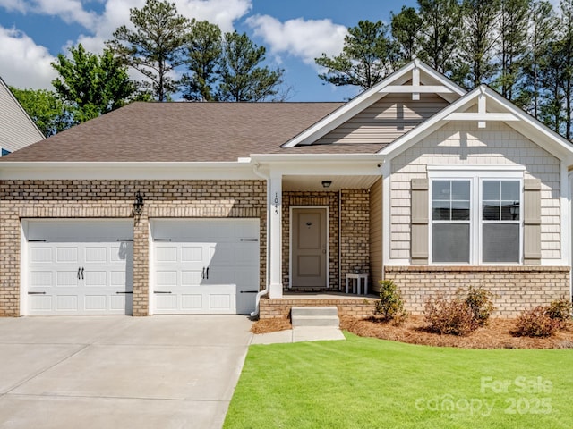 craftsman-style home featuring a front lawn, a garage, brick siding, driveway, and roof with shingles