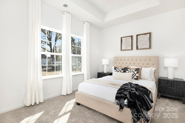 bedroom with a tray ceiling, visible vents, baseboards, and carpet