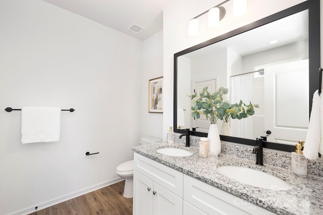 bathroom with baseboards, a sink, toilet, and wood finished floors