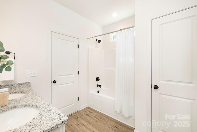 full bath featuring shower / bath combo, wood finished floors, double vanity, and a sink