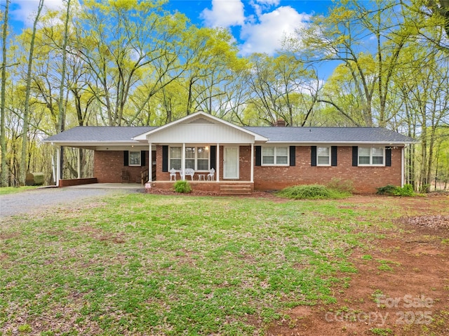 ranch-style home with a carport, a chimney, brick siding, a front lawn, and gravel driveway