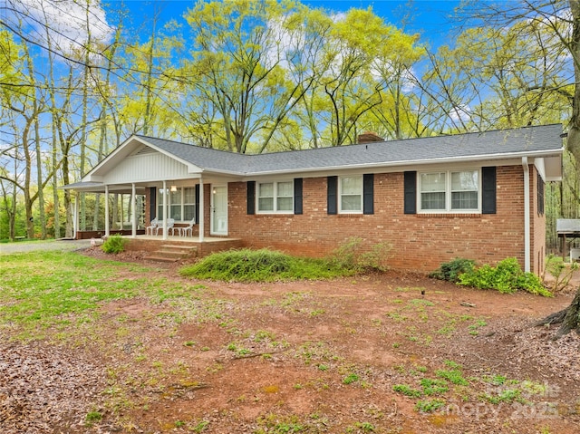 single story home with brick siding, a chimney, and covered porch