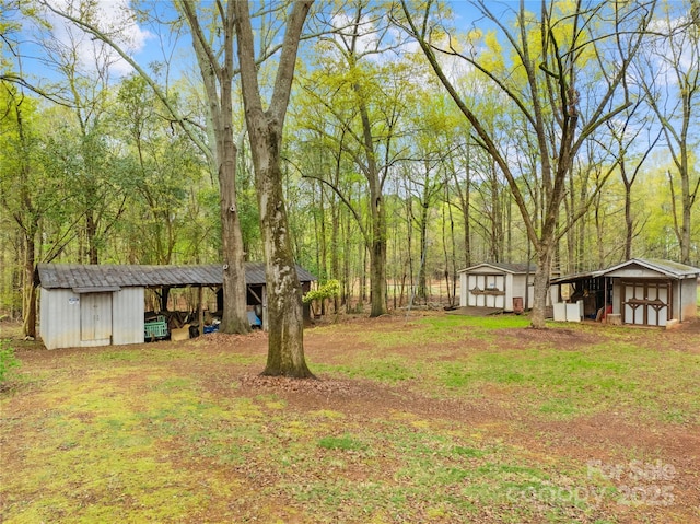 view of yard with a storage shed, a view of trees, an outdoor structure, and a pole building