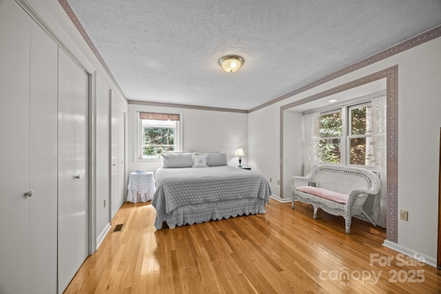 63 Chestnut Forest Rd, Fairview, NC 28730 - bedroom with ornamental molding, a textured ceiling, visible vents, light wood-style flooring, and baseboards