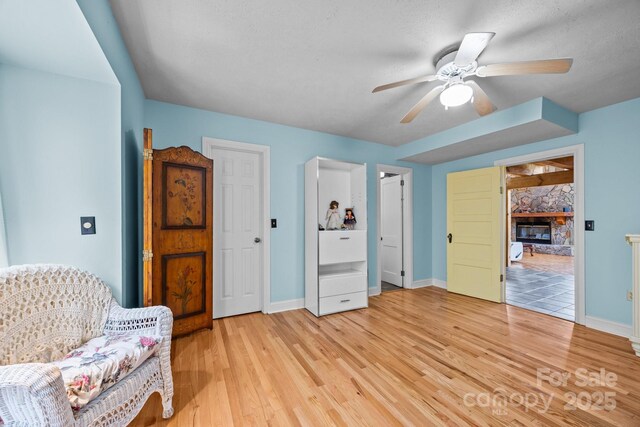63 Chestnut Forest Rd, Fairview, NC 28730 - sitting room featuring light wood finished floors, baseboards, ceiling fan, and a stone fireplace