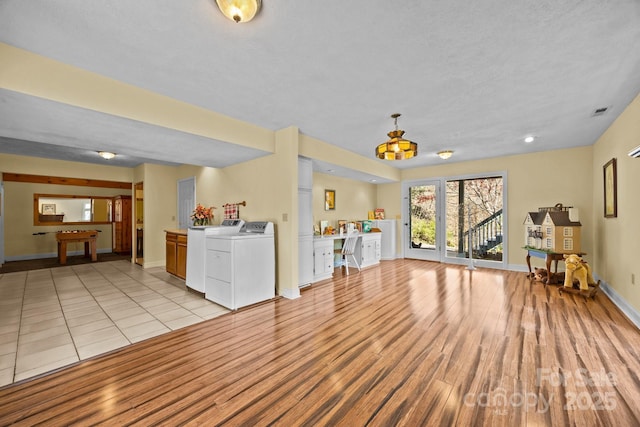 63 Chestnut Forest Rd, Fairview, NC 28730 - unfurnished living room with a textured ceiling, baseboards, light wood finished floors, visible vents, and washer and clothes dryer