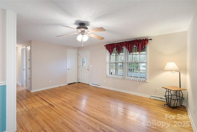 interior space featuring baseboard heating, baseboards, a ceiling fan, and wood finished floors